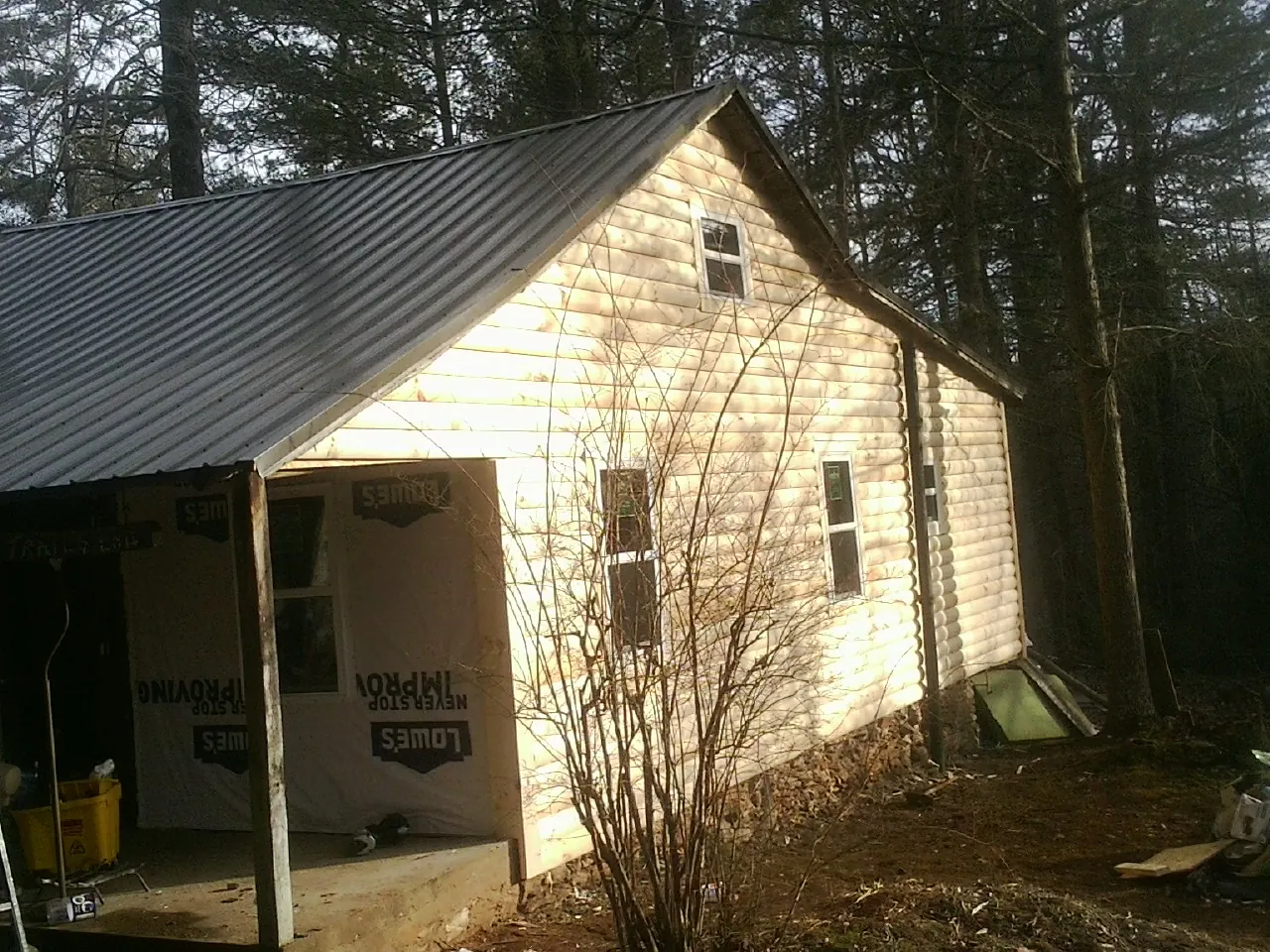 Log siding gable end under a dark metal roof edge in Romayor