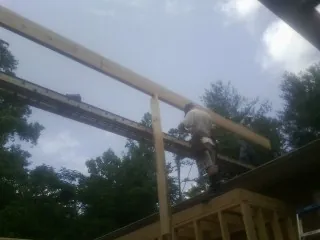 Carpenter setting a ridge beam over a new addition frame — Ice Dam Removal by Roofing Brothers in Romayor