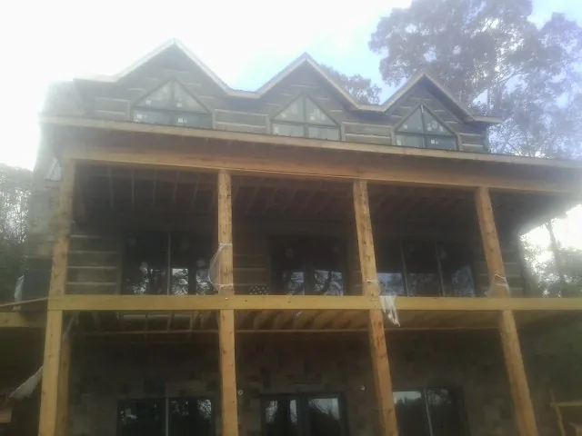 Dormers and porch framing on a large log home under construction — Roof Coating work by our crew in Romayor