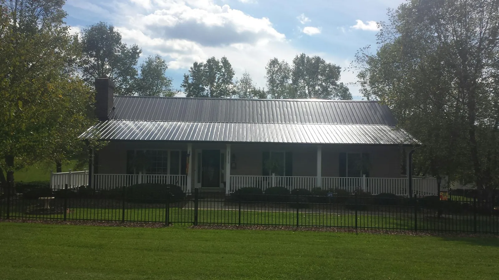 Gray metal roof on a brick ranch with a full width front porch — Gutter Guard Installation work by our crew in Romayor