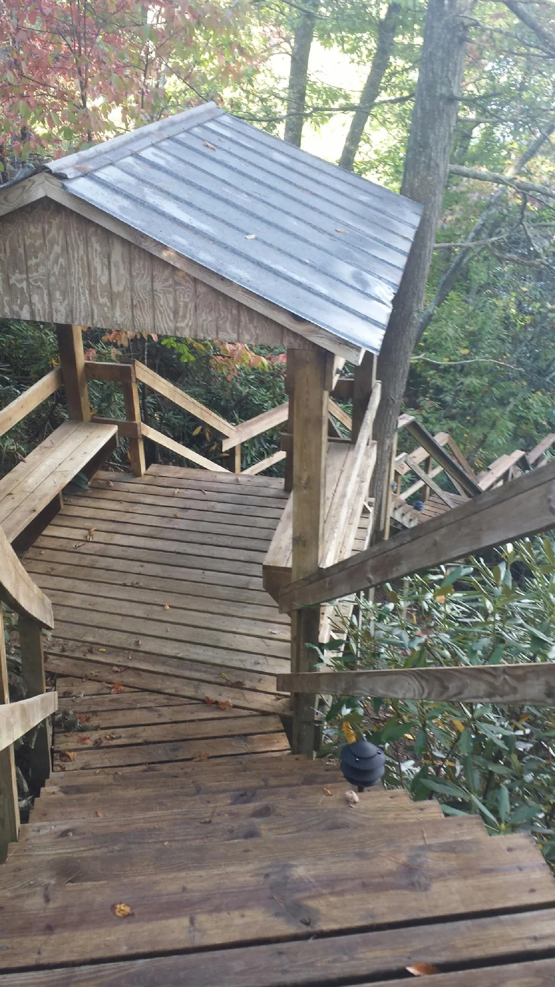 Metal roofed shelter over wooden steps on a wooded walkway — Skylight Repair & Installation work by our crew in Romayor