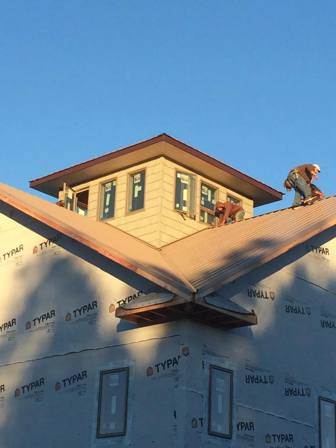 Roofers working around a rooftop cupola on a new metal roof at sunset — Roof Waterproofing in Romayor by Roofing Brothers